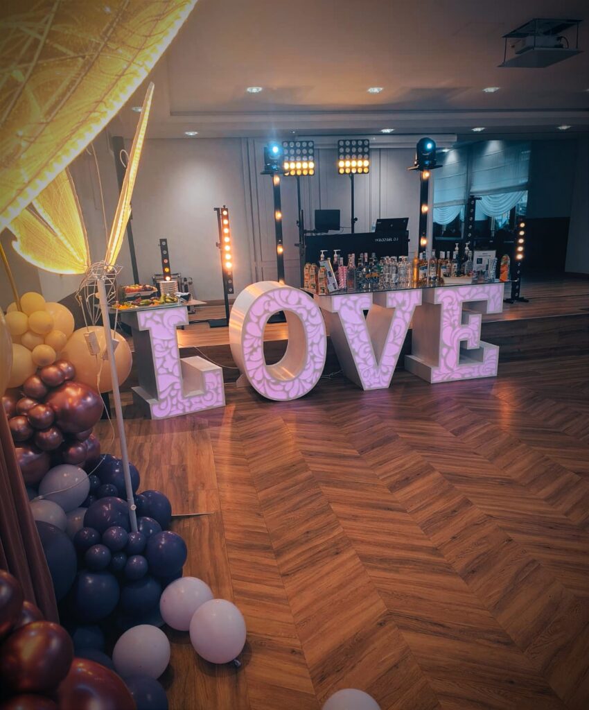 Podświetlany napis LOVE i balony na sali weselnej