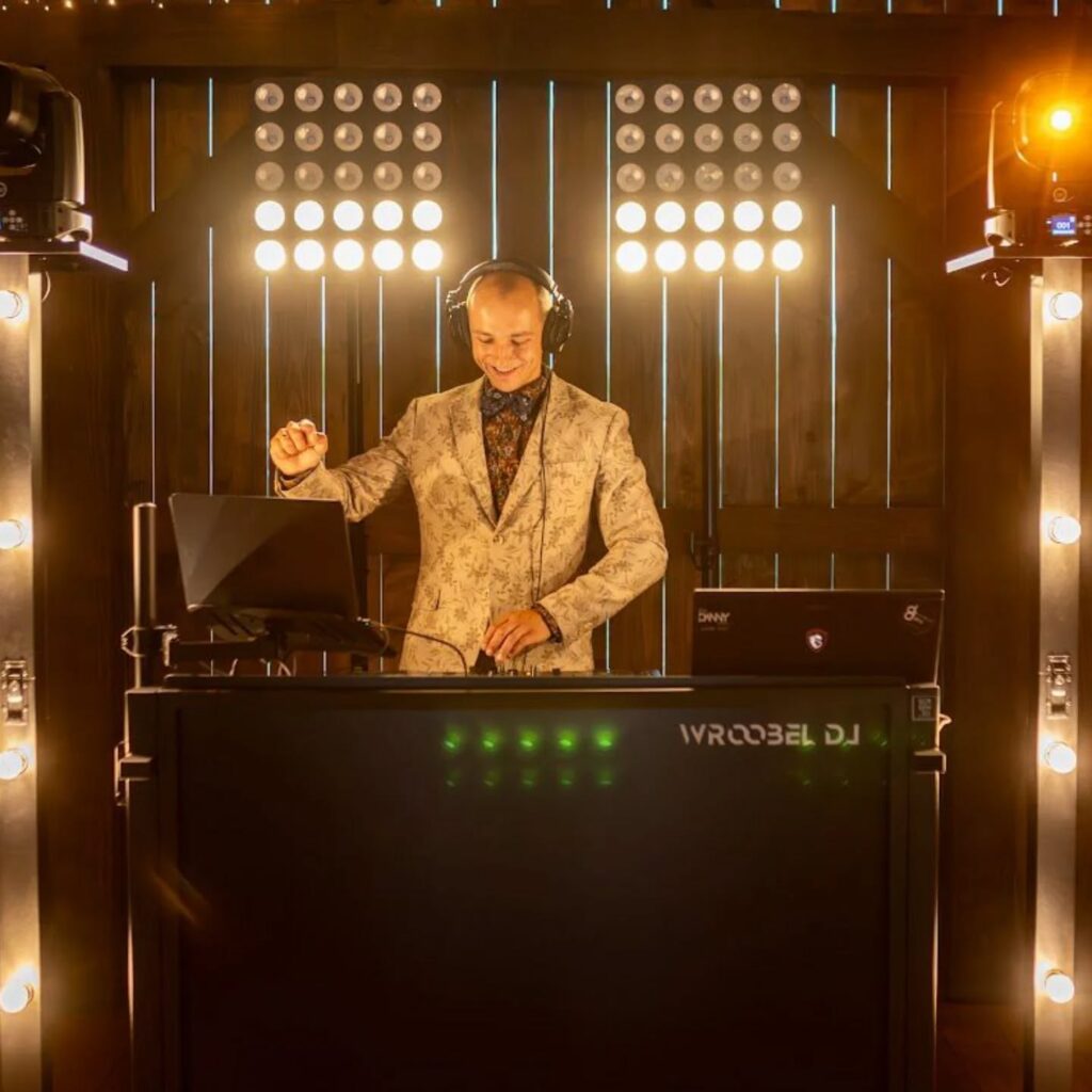 Daniel Wróbel przy konsolecie DJ-skiej podświetlonej żarówkami