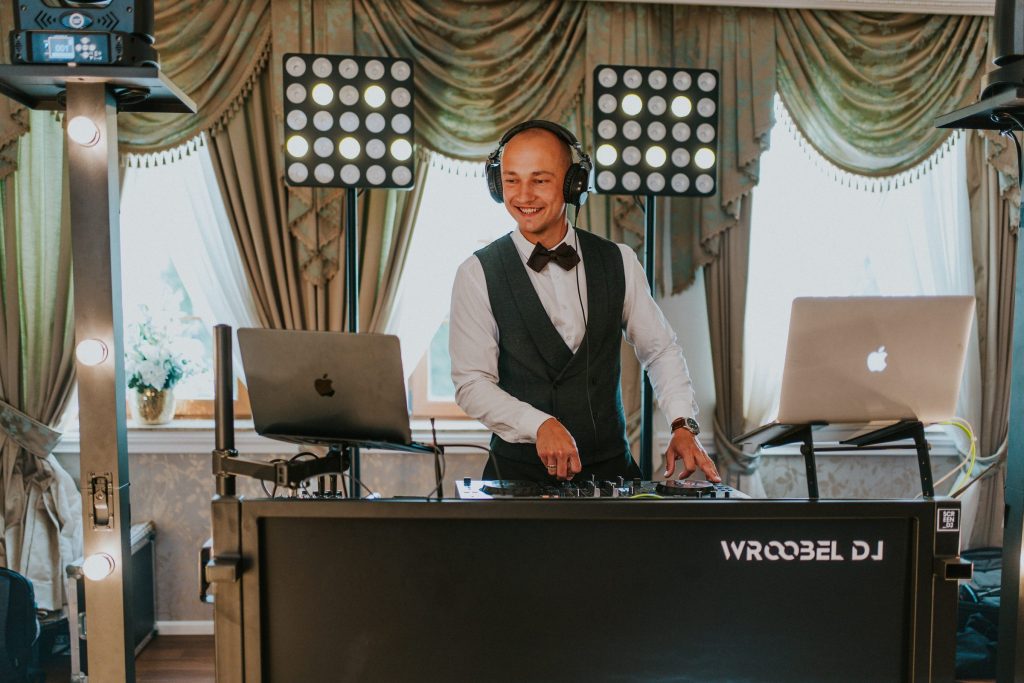 Daniel Wróbel w słuchawkach przy konsolecie WroobelDJ, za nim panele świetlne