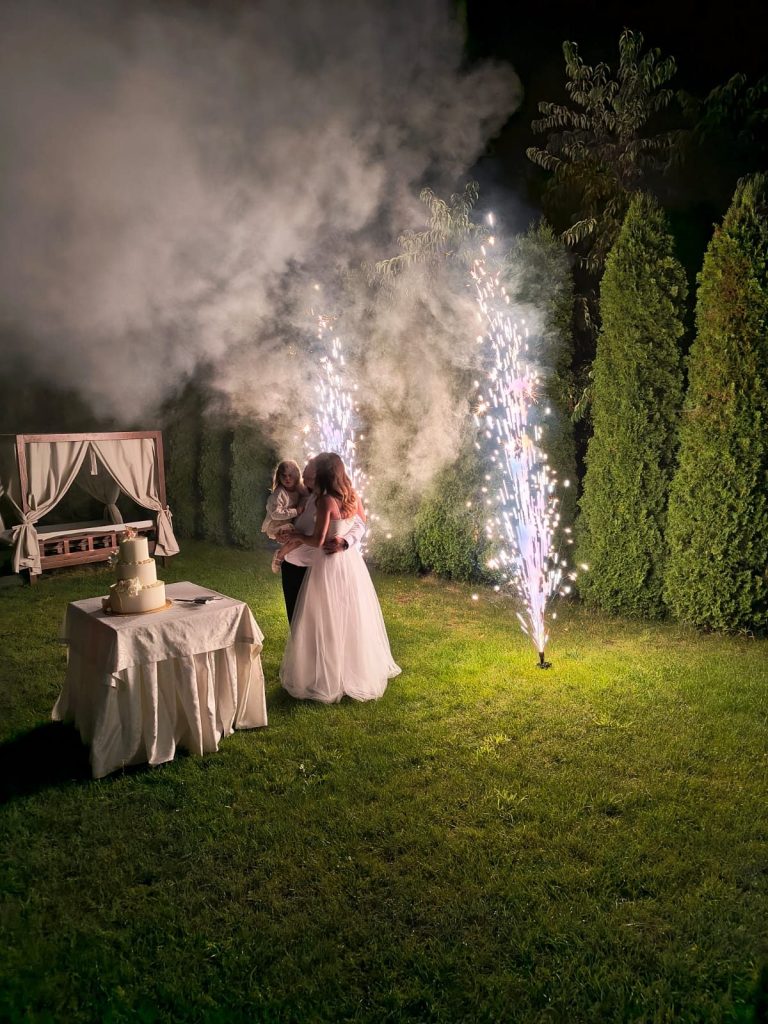 Para młoda nocą w ogrodzie przy torcie, obok fontanna iskier